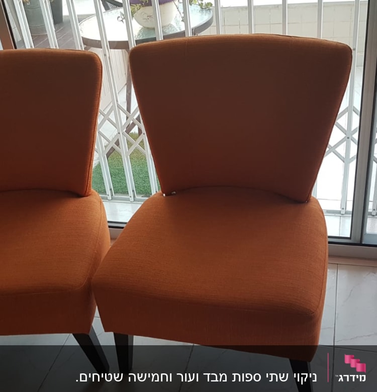 שני כיסאות כתומים ליד חלון זכוכית